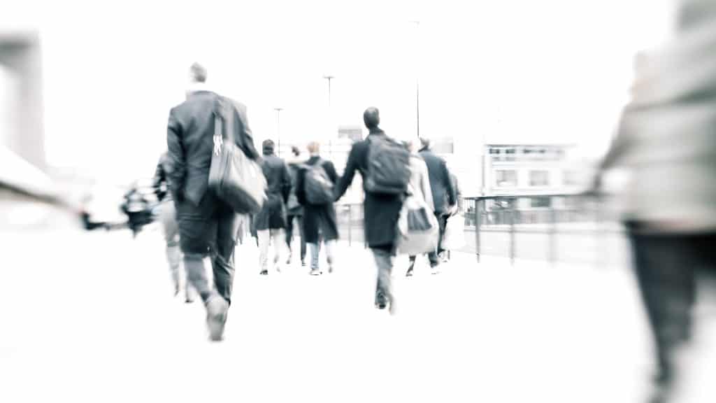 blurry, black and white image of men walking on a sidewalk