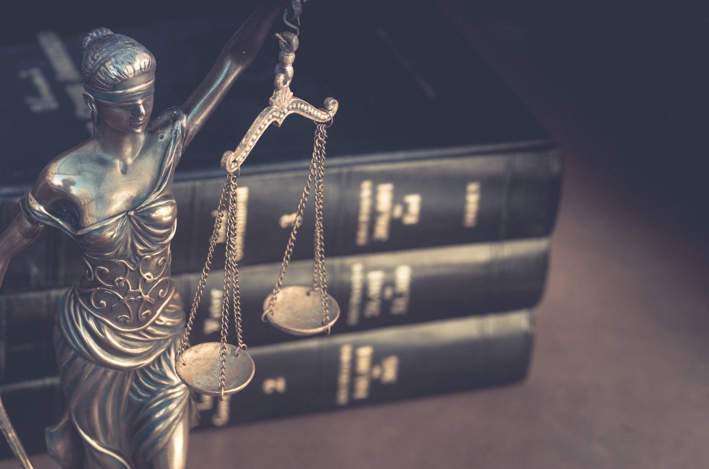 Lady Justice statue in front of blurred books